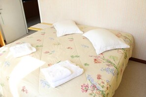 A bed with floral bedding, two pillows, and two folded towels. - Cozy house, close to the center of Canela. 4 bedrooms and pets allowed. (Canela)