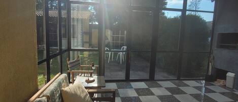 Aurinkoinen huone, jossa on ruutukuviollinen lattia, tyynyillä varustettu sohva ja näkymä suurista ikkunoista.