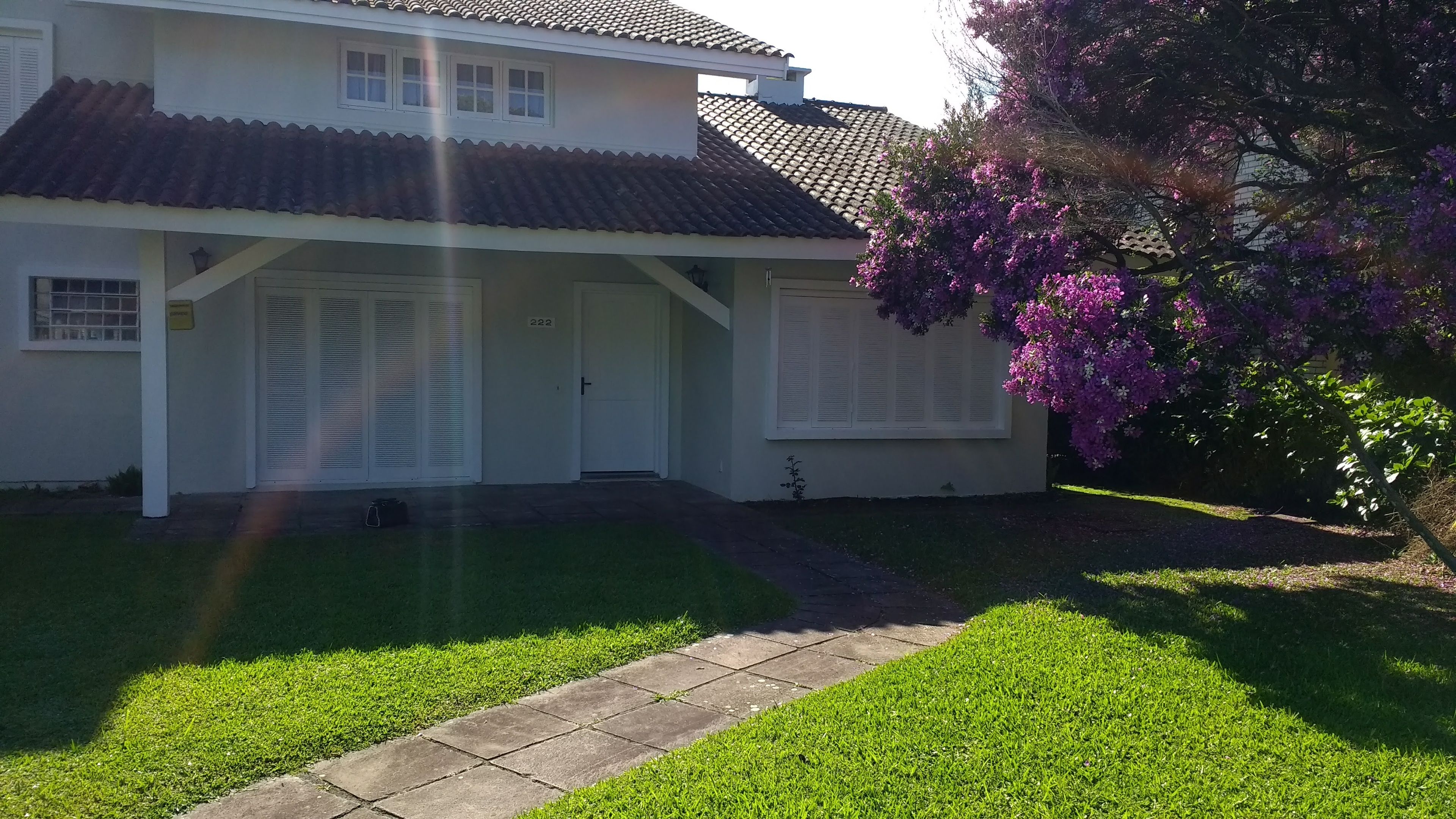A two-story house with a tiled roof, a front porch, and a well-maintained lawn.