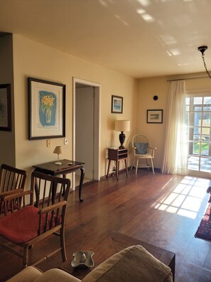 A room with wooden flooring, a door, a chair, a table, and a lamp. - Cozy house, close to the center of Canela. 4 bedrooms and pets allowed. (Canela)