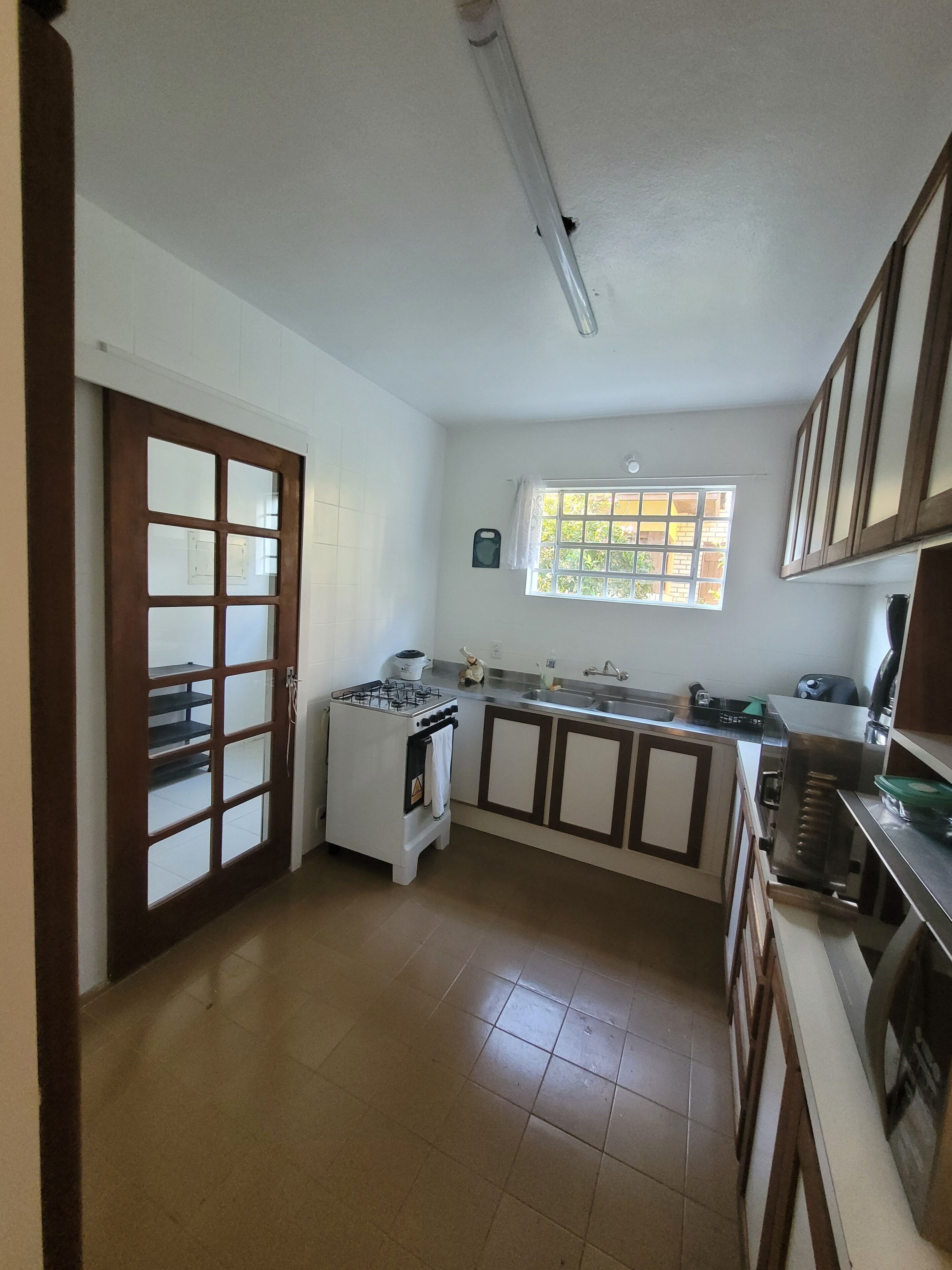 Una cocina con estufa a gas, pileta, alacenas y ventana con vista.