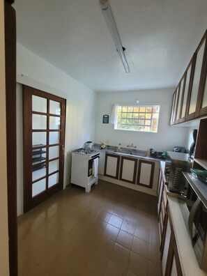 A kitchen with a gas stove, a sink, cabinets, and a window with a view. - Cozy house, close to the center of Canela. 4 bedrooms and pets allowed. (Canela)
