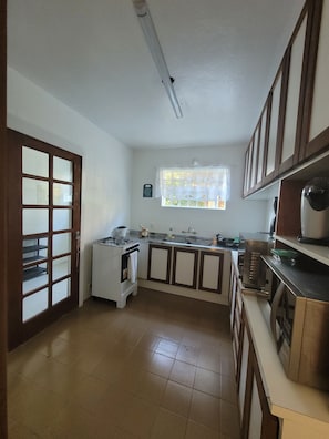 A kitchen with a gas stove, sink, cabinets, and a window. - Cozy house, close to the center of Canela. 4 bedrooms and pets allowed. (Canela)