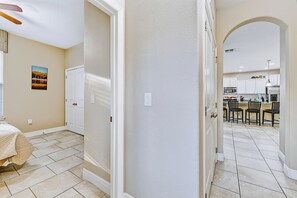 A hallway leading to a kitchen with white cabinets and a dining area with chairs. - Orlando Escape! Pool-Spa-Theater-GameRoom:4-15 PPL (Davenport)