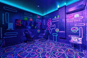 A room with neon wall art, a gaming chair, and a neon-lit floor. - Orlando Escape! Pool-Spa-Theater-GameRoom:4-15 PPL (Davenport)