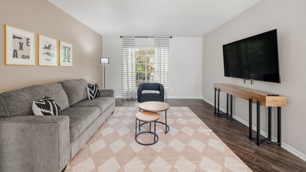 A living room with a sofa, a coffee table, a TV, and framed pictures on the wall. - Chic Houston Apt 2BR 2BA (Houston)