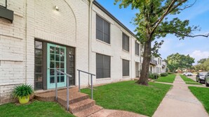 A two-story building with a green door, a small set of steps leading to the entrance, and a tree in the front yard. - Chic Houston Apt 2BR 2BA (Houston)