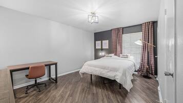 A bedroom with a bed, a desk, and a chair.