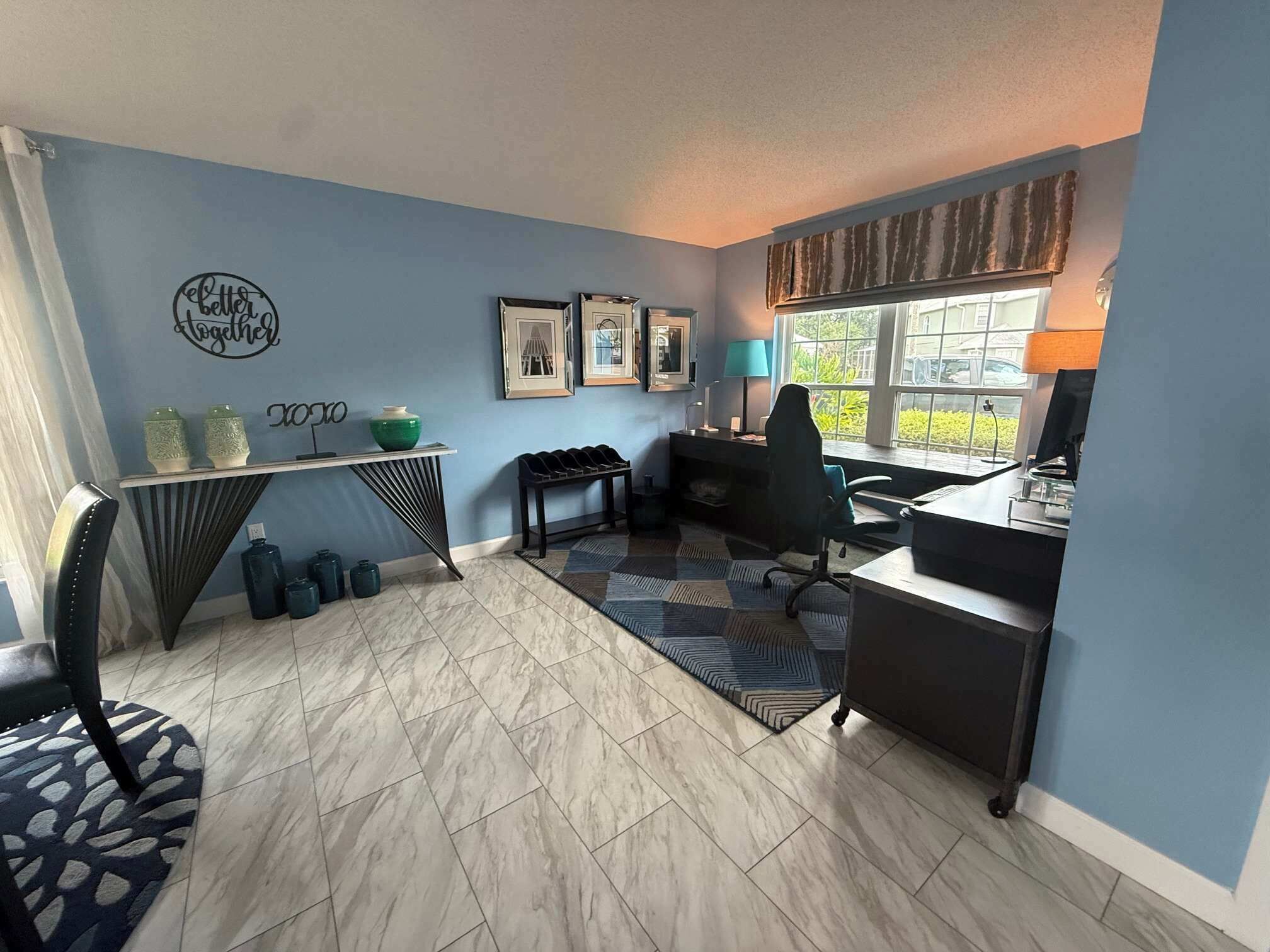 Habitación con escritorio, silla y ventana con vistas.