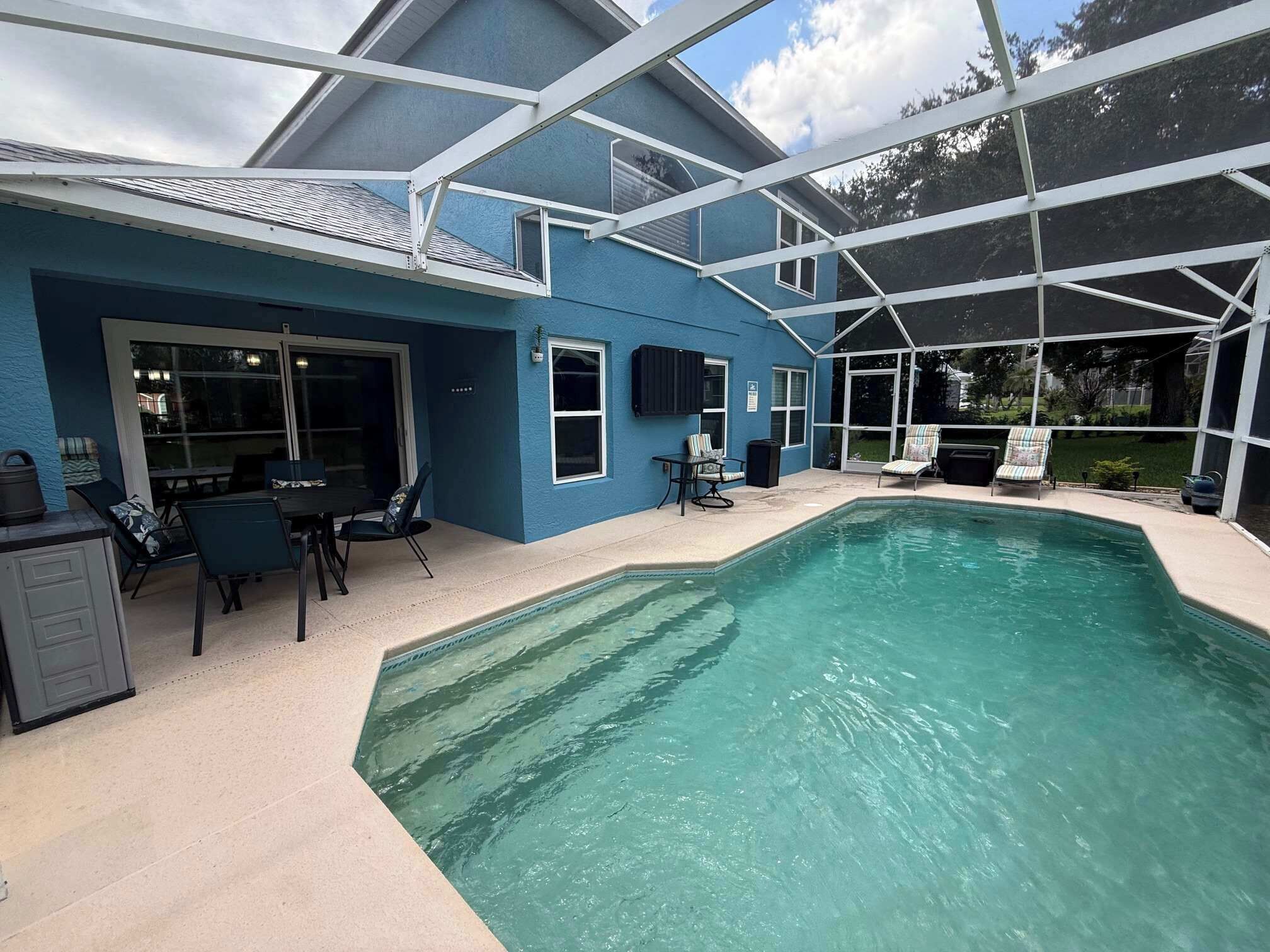 A house with a swimming pool, a covered patio, and a dining area.