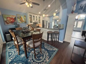 A modern kitchen with white cabinets, a dining table with chairs, and a patterned rug. - Peaceful Backyard Paradise (Haines City)