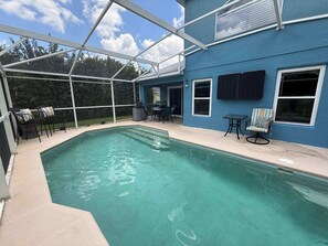 A swimming pool with a covered patio area, a barbecue grill, and outdoor seating. - Peaceful Backyard Paradise (Haines City)