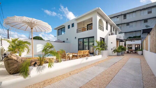 Uma casa moderna de dois andares, com um pátio, área de estar externa e piscina.