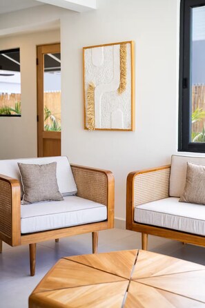 A modern living room with two wicker sofas, a wooden coffee table, and a large abstract painting on the wall. - Spacious 4-bedroom house in fantastic San Juan with AC (San Juan)