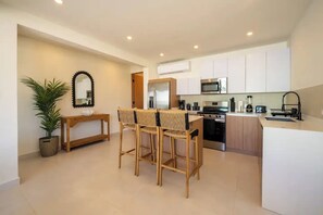 A modern kitchen with white cabinets, a stainless steel oven, and a microwave. There is a dining area with a wooden table and chairs. - Spacious 4-bedroom house in fantastic San Juan with AC (San Juan)