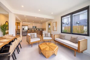 A modern interior with a dining area, sofas, and a kitchen in the background. - Spacious 4-bedroom house in fantastic San Juan with AC (San Juan)