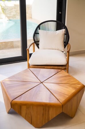 A modern lounge area with a wooden coffee table and a wicker chair with a white cushion. - Spacious 4-bedroom house in fantastic San Juan with AC (San Juan)