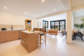 A modern kitchen with a central island, dining area with wooden furniture, and large windows. - Spacious 4-bedroom house in fantastic San Juan with AC (San Juan)