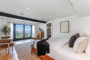 Un dormitorio moderno con una cama grande, vistas a la ciudad y un vestidor.