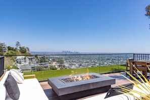 Una terraza con una fogata, mobiliario exterior y vistas a la ciudad.