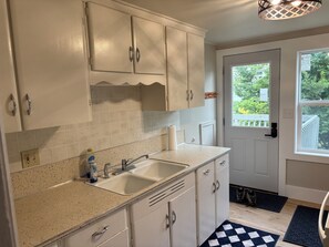 A kitchen with white cabinets, a sink, and a window. - Stay in America's Pumpkin Capital! Furnished Apartment Near Peoria Hospitals (Morton)