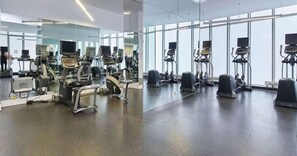 Et fitnessrum med diverse træningsmaskiner, et stort spejl og en rummelig indretning.