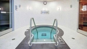 En lille swimmingpool indendørs med et skilt, der står 'SHADOW AREA', omgivet af et flisebelagt gulv med en afløb i midten.