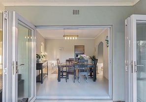 Una porta aperta che dà su un'area pranzo con tavolo e sedie, un lampadario e vista su una scala.