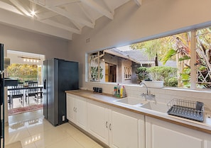 Una cucina moderna con mobili bianchi, un frigorifero in acciaio inossidabile e una finestra vista giardino.