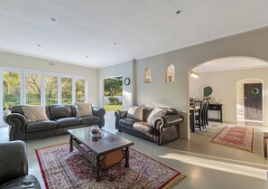 Ein geräumiges Wohnzimmer mit einer großen Sofagarnitur, einem Couchtisch und einem Essbereich mit Tisch und Stühlen.