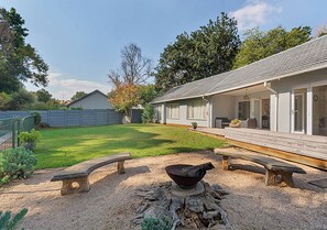 Ein Garten mit Feuerstelle, Bänken und einer Holzterrasse.