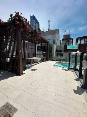 Eine Dachterrasse mit Swimmingpool, Sitzgelegenheit und Blick auf die Stadtlandschaft.