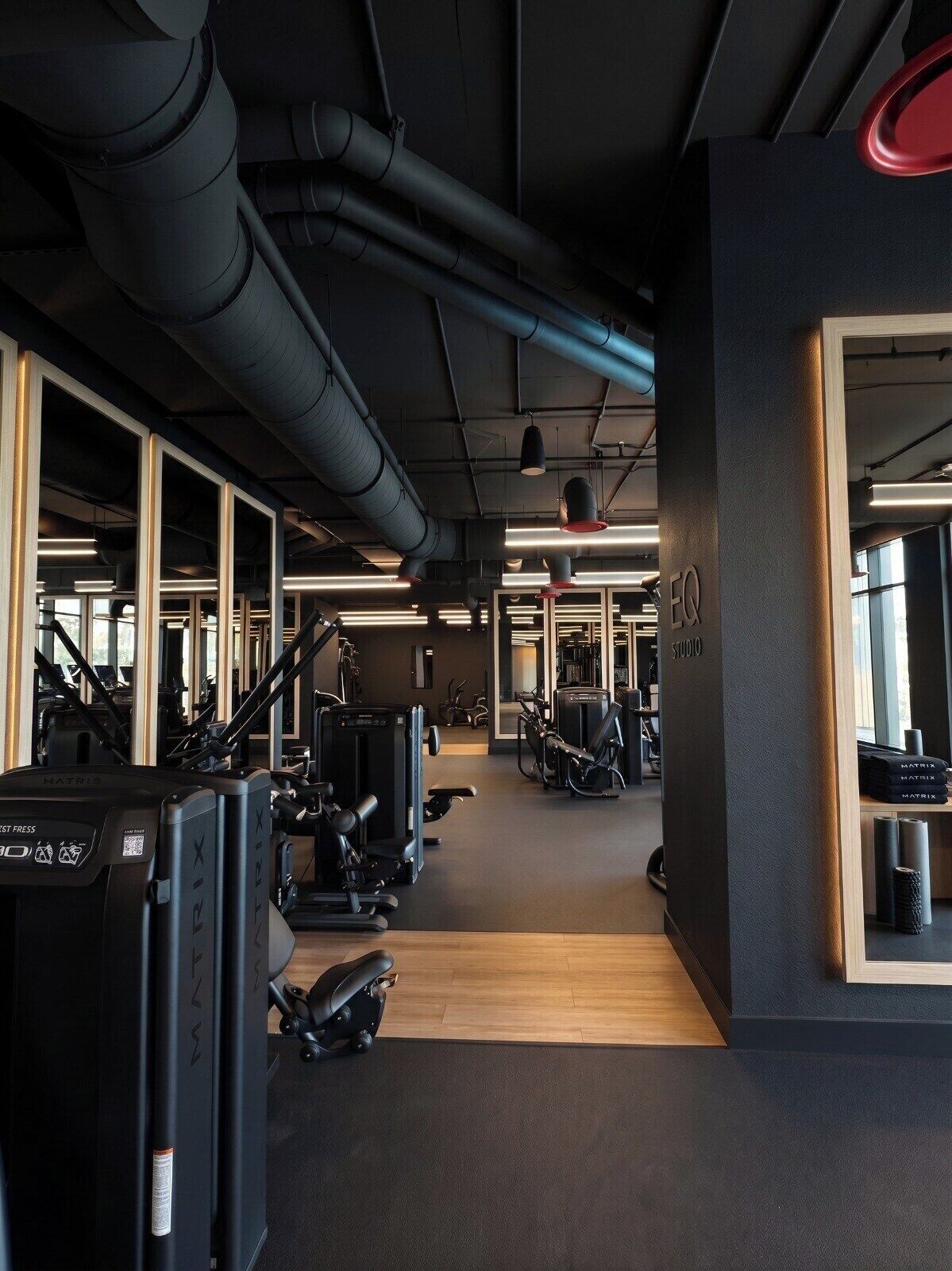 Une salle de sport équipée de matériel d’exercice, dotée de murs couverts de miroirs et d’un plancher en bois.