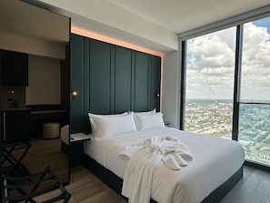 Ein modernes Hotelzimmer mit einem großen Bett, einem Schreibtisch und Blick auf die Stadt.