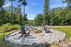 Un'area relax all'aperto con poltrone Adirondack e un braciere in pietra.