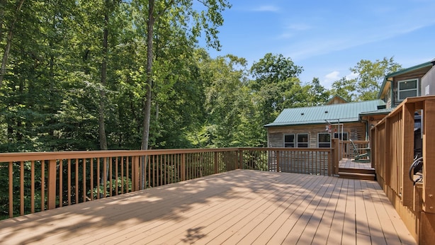 A wooden deck with a view of a cabin surrounded by trees.