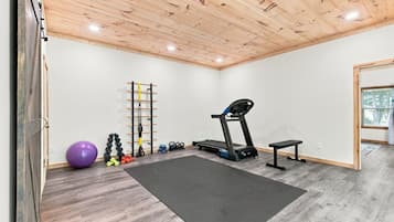Une salle de sport à domicile équipée d’une barre de traction, d’un ballon d’exercice, d’haltères, de kettlebells et d’un tapis de course.