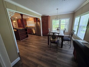 Una cocina con armarios de madera, un refrigerador y una zona de comedor con mesa y sillas.