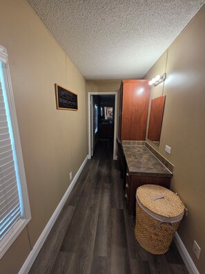 A hallway with a wooden floor, a basket, a mirror, and a sign on the wall. - 1800 sq ft, 3-bed, 2- bath, 2 plus acres in Gulf Hammock Florida. (Morriston)