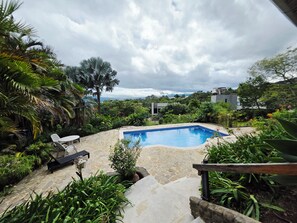 Une piscine entourée d’une végétation luxuriante, de sentiers en pierre et de mobilier d’extérieur.