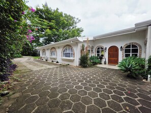 Une maison avec une allée pavée de pierres, des fenêtres en arc de cercle et une porte en bois.