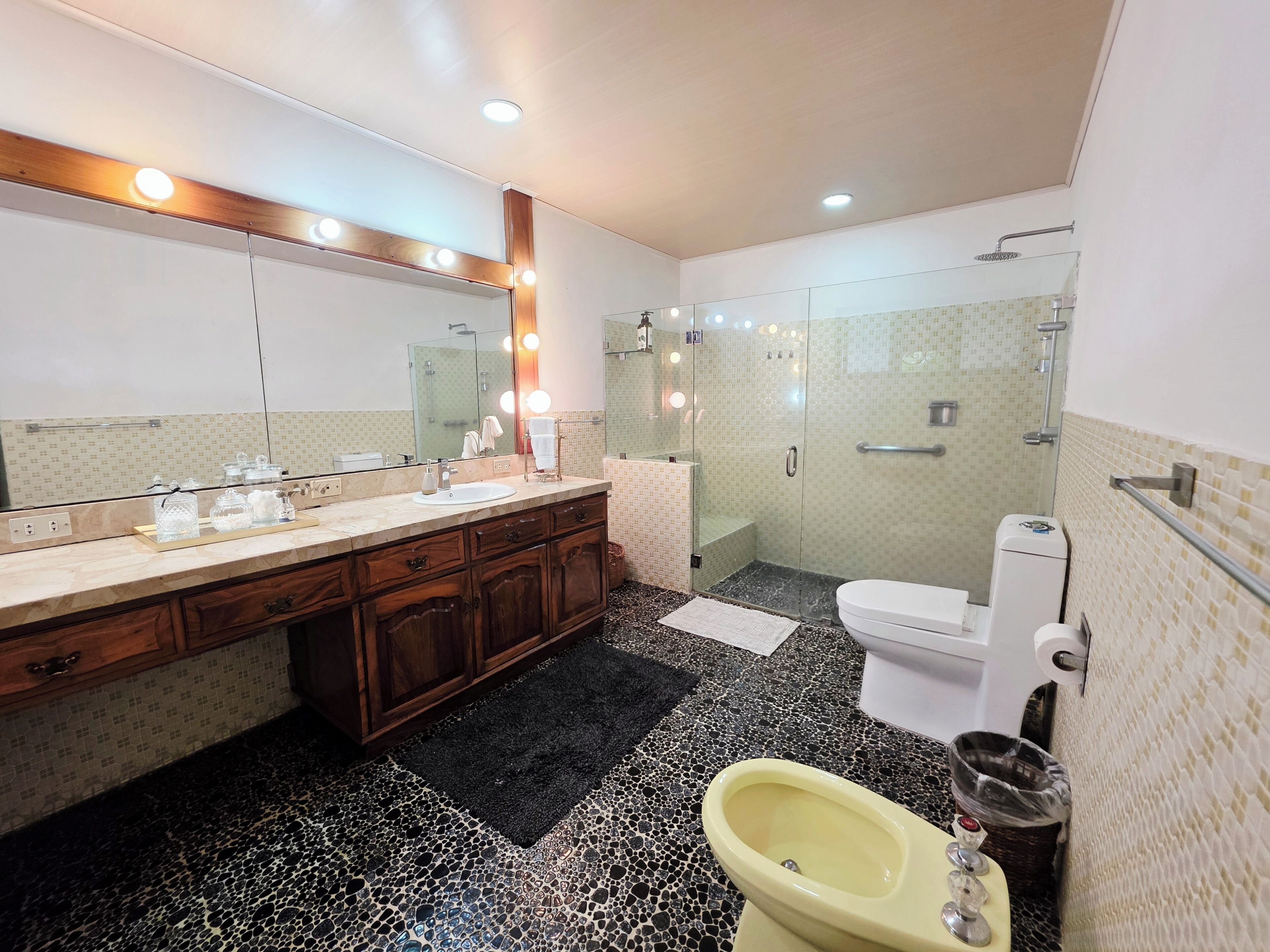 A modern bathroom with a vanity, mirror, and shower area.