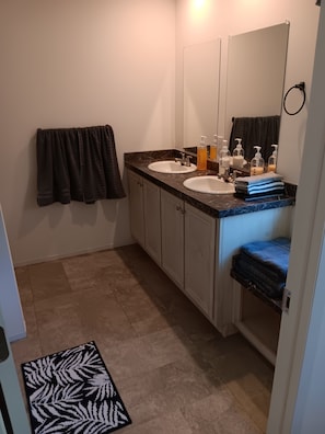 A bathroom with two sinks, a mirror, and a towel rack.