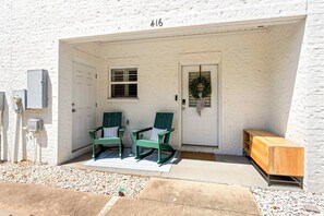 A white building with a number '416' above the door, two green chairs with cushions, a wooden bench, and a small window with shutters. - NEW! 2 Bed/2.5 Bath - 0.7 Mi From Jordan-Hare Stadium (Auburn)