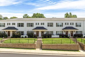 A two-story building with a symmetrical facade, evenly spaced windows, and a central entrance with steps leading up to it. - NEW! 2 Bed/2.5 Bath - 0.7 Mi From Jordan-Hare Stadium (Auburn)