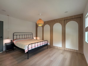 A bedroom with a bed, bedside table, lamp, and a wall with three arched niches. - Villa with Office, Gym, Jacuzzi & Dryer near CIQ (Johor Bahru)