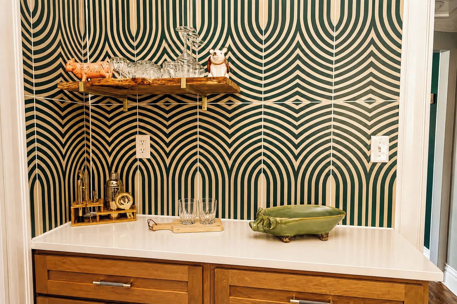 Een keuken met behang met een patroon, een houten aanrecht en een groene kom.
