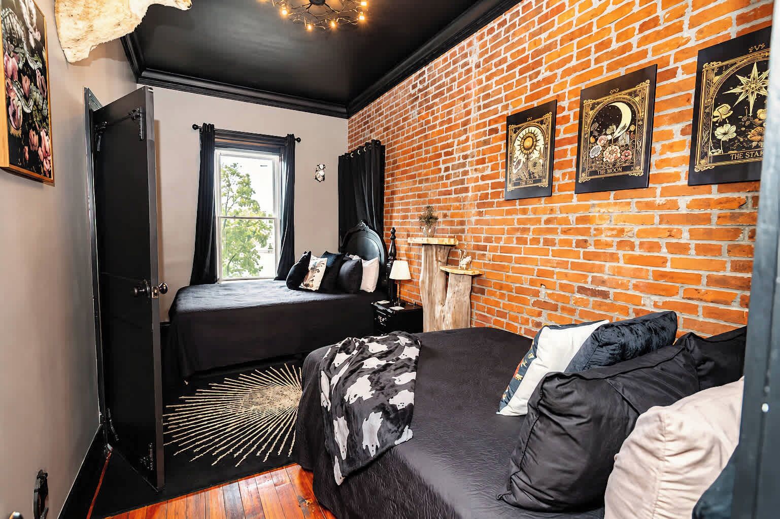 Ein Zimmer mit Bett, Fenster, Backsteinwand und Kamin.