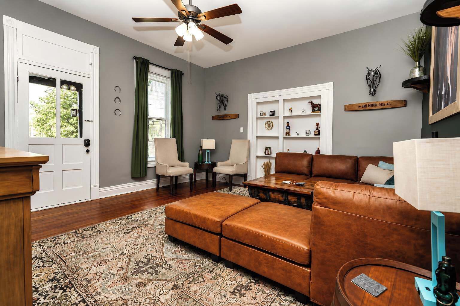 A living room with a brown leather sofa, a wooden coffee table, and a patterned rug.