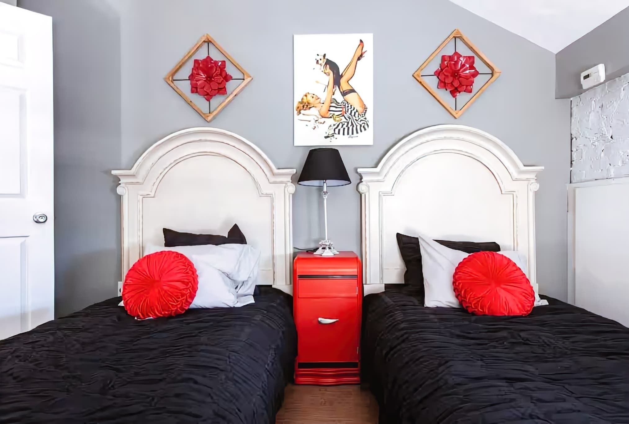 A hotel room with two beds, a red dresser, and artwork on the wall.